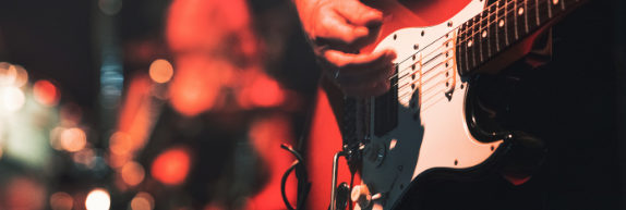 Guitarrista toca durante show com iluminação vermelha